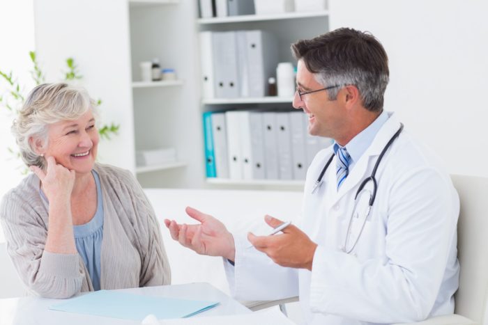 Doctor discussing with senior patient at table fall prevention